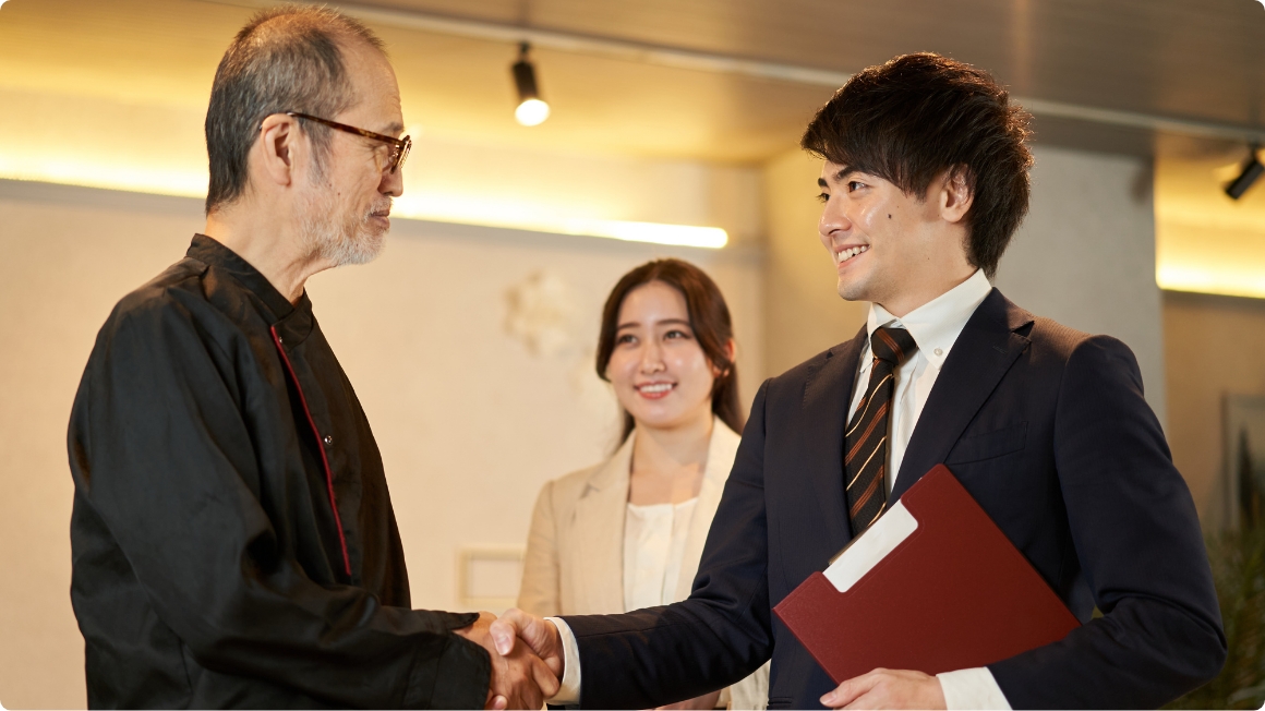 店舗オーナー様と弊社社員が握手している様子